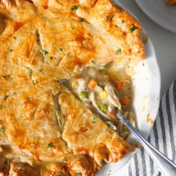 Overhead view of chicken pot pie in a white pie dish with a section cut out.