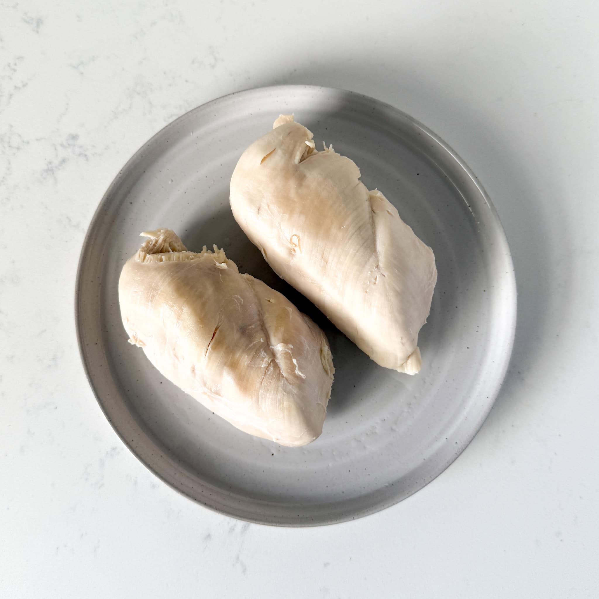 Boiled chicken breasts resting on a plate.