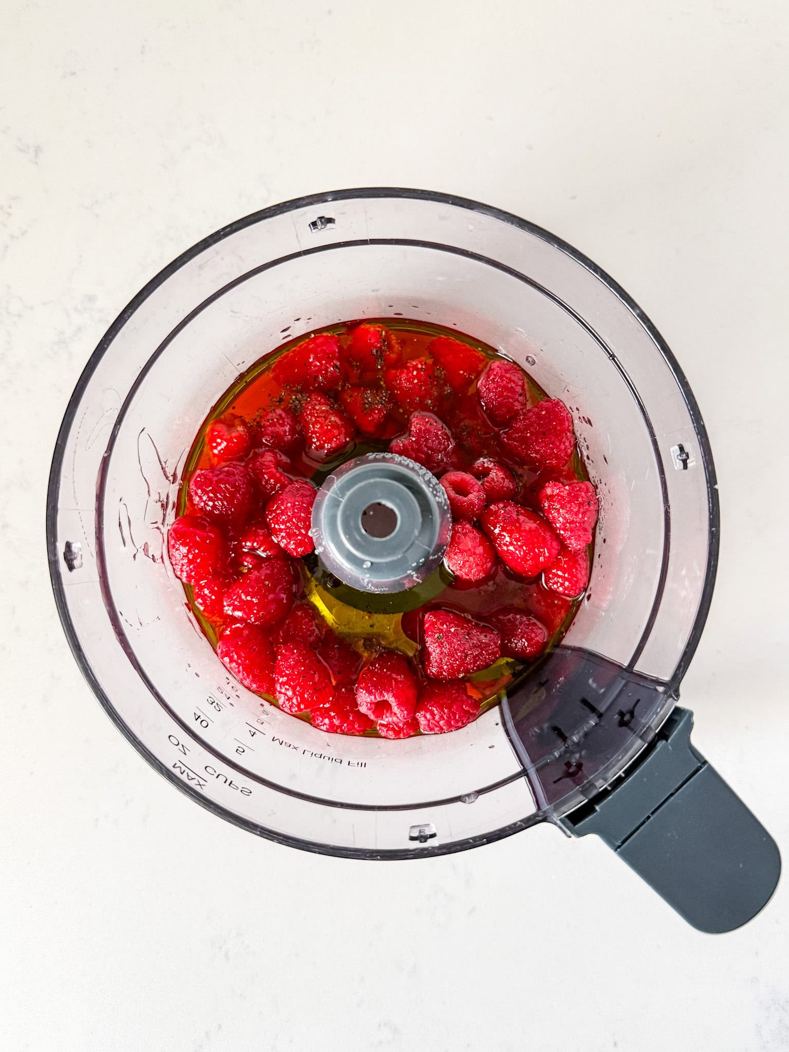 Overhead view of raspberry dressing ingredients in a food processor.