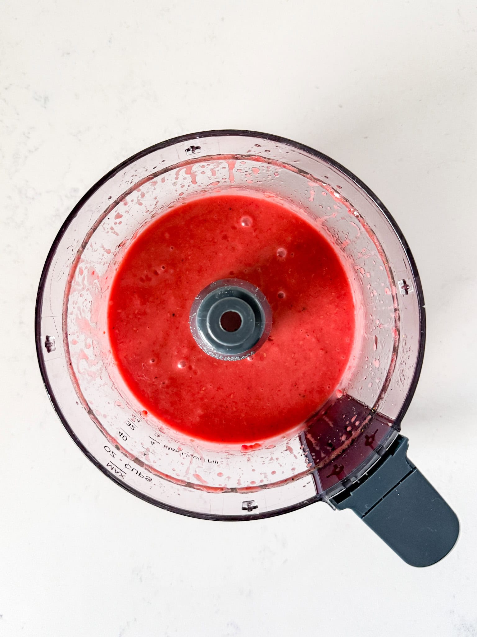 Overhead view of raspberry dressing blended in a food processor.