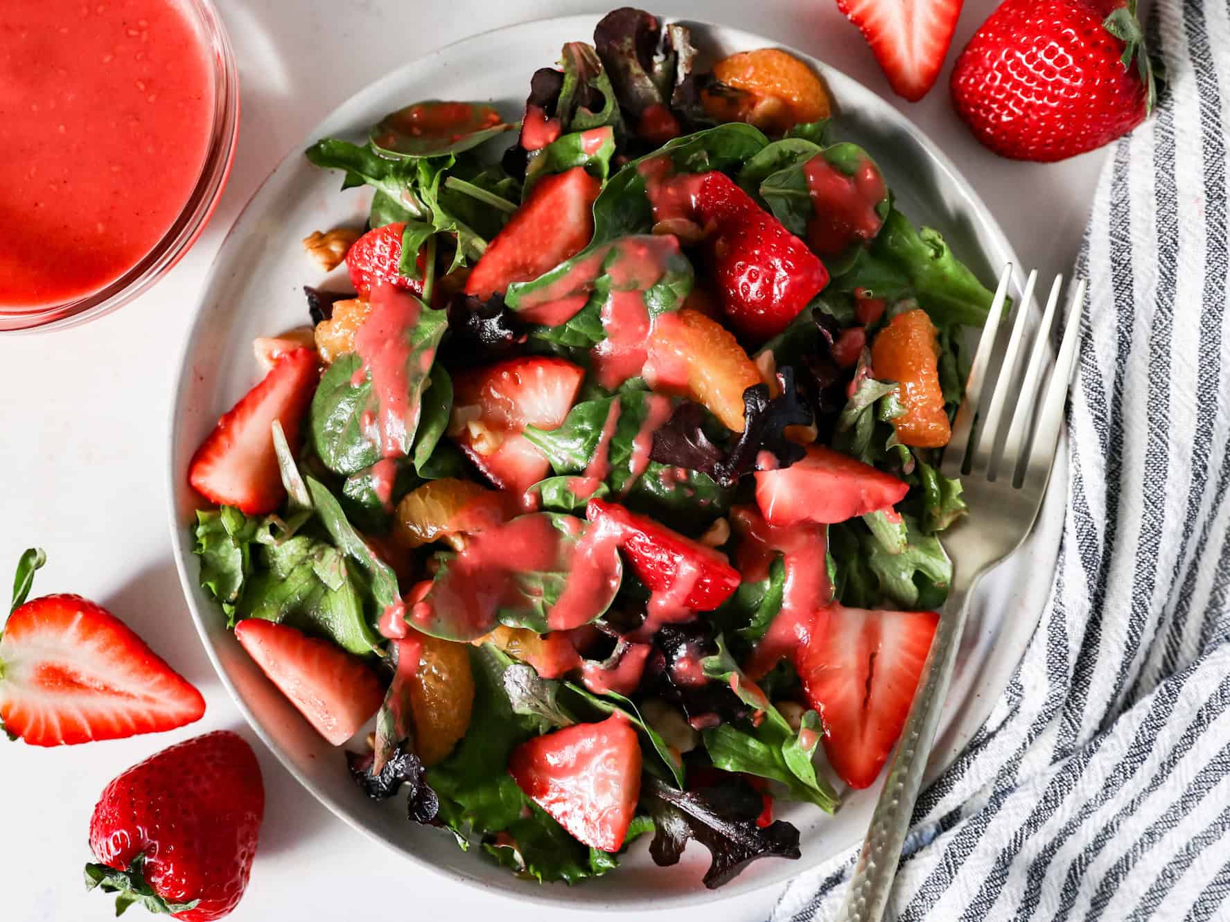 Overhead view of raspberry vinaigrette dressing drizzled over a strawberry spinach salad.