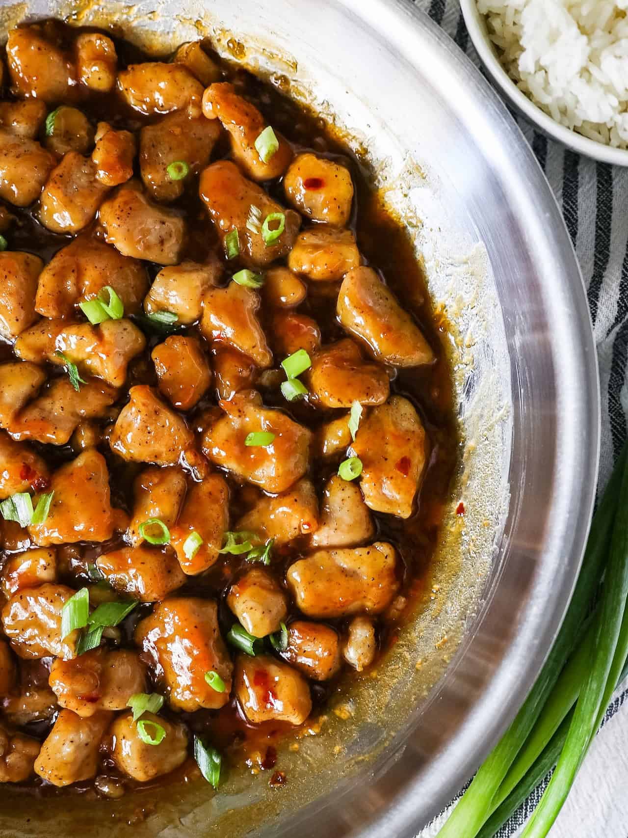 Overhead view of honey garlic chicken in a large stainless steel skillet.