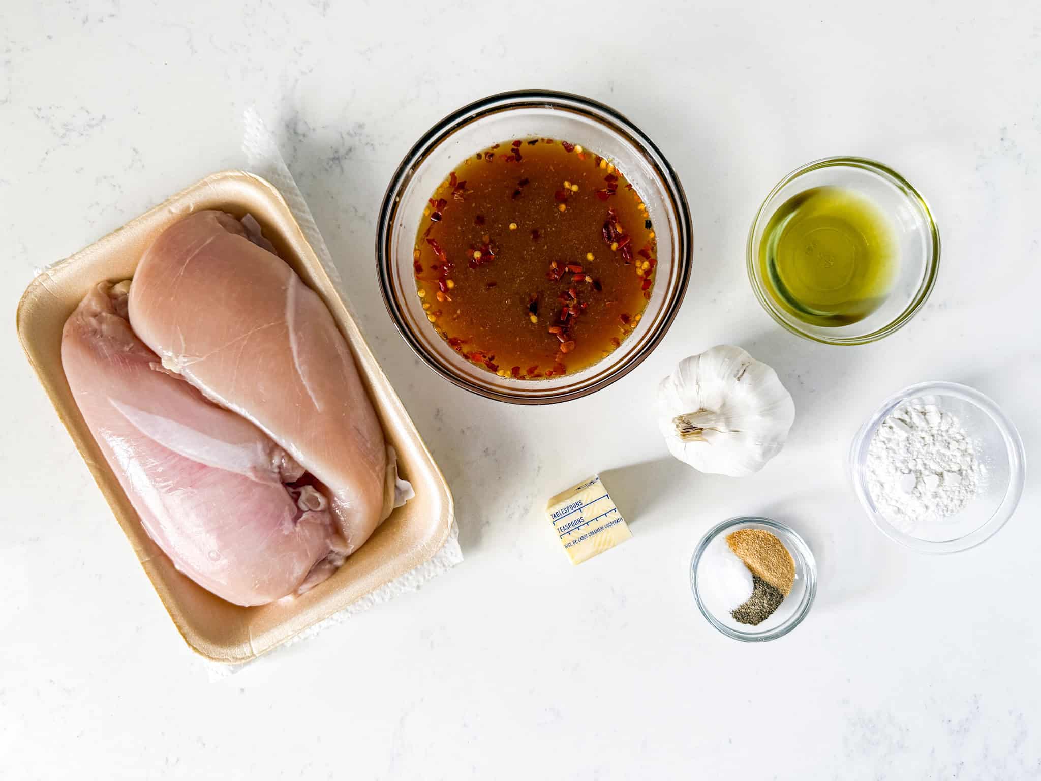 Honey garlic chicken ingredients spread out on a white countertop.