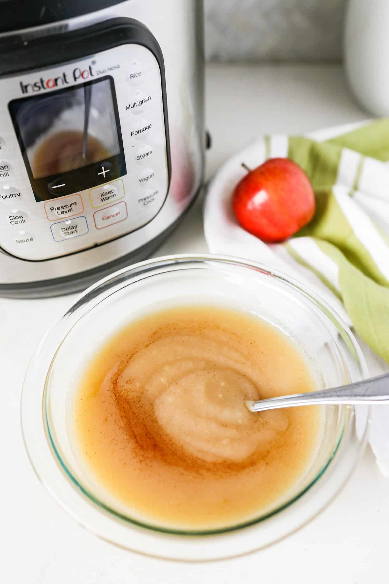 Applesauce with cinnamon sprinkled on top sitting beside an instant pot