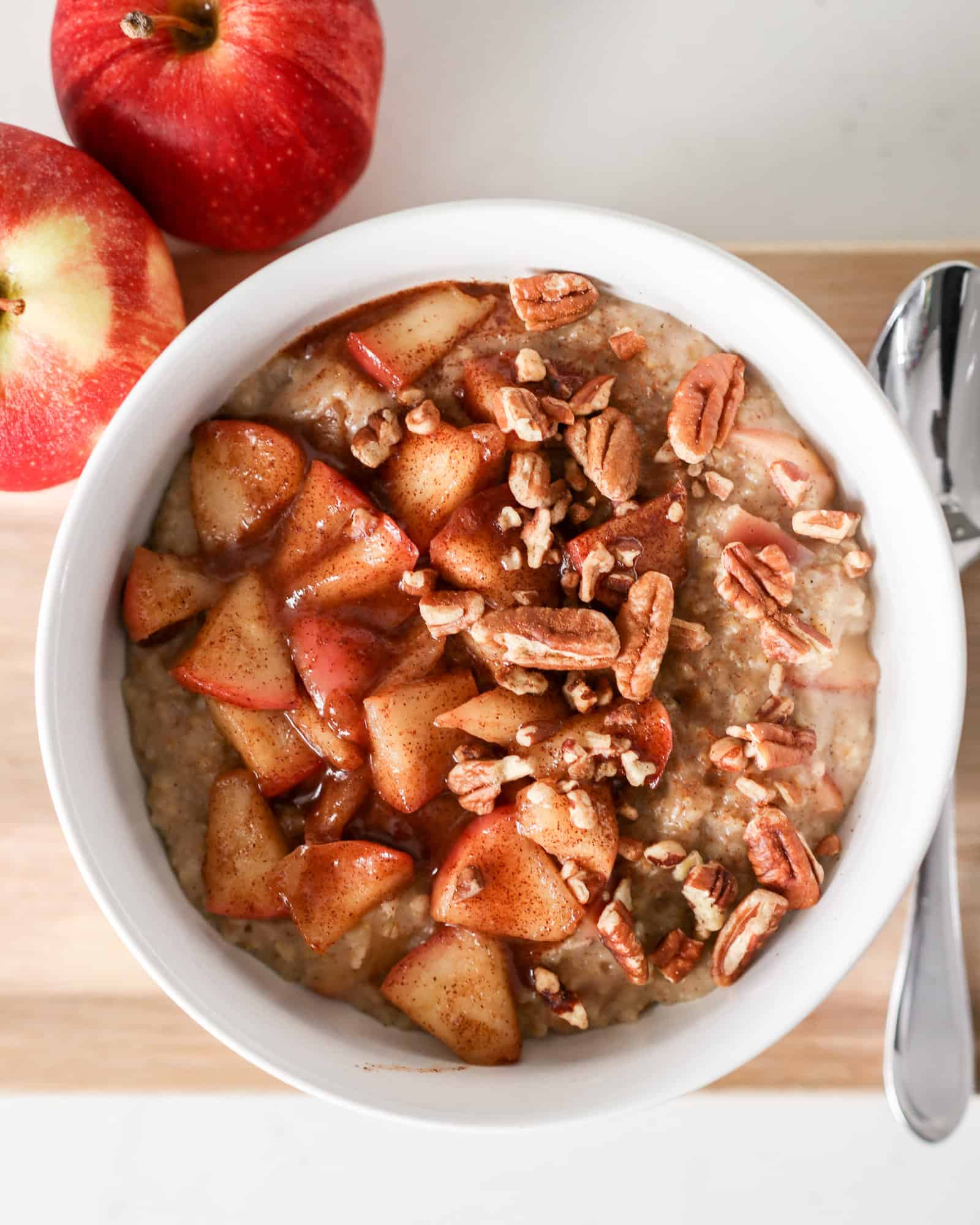 Apple Cinnamon Oatmeal topped with pecans in a white bowl
