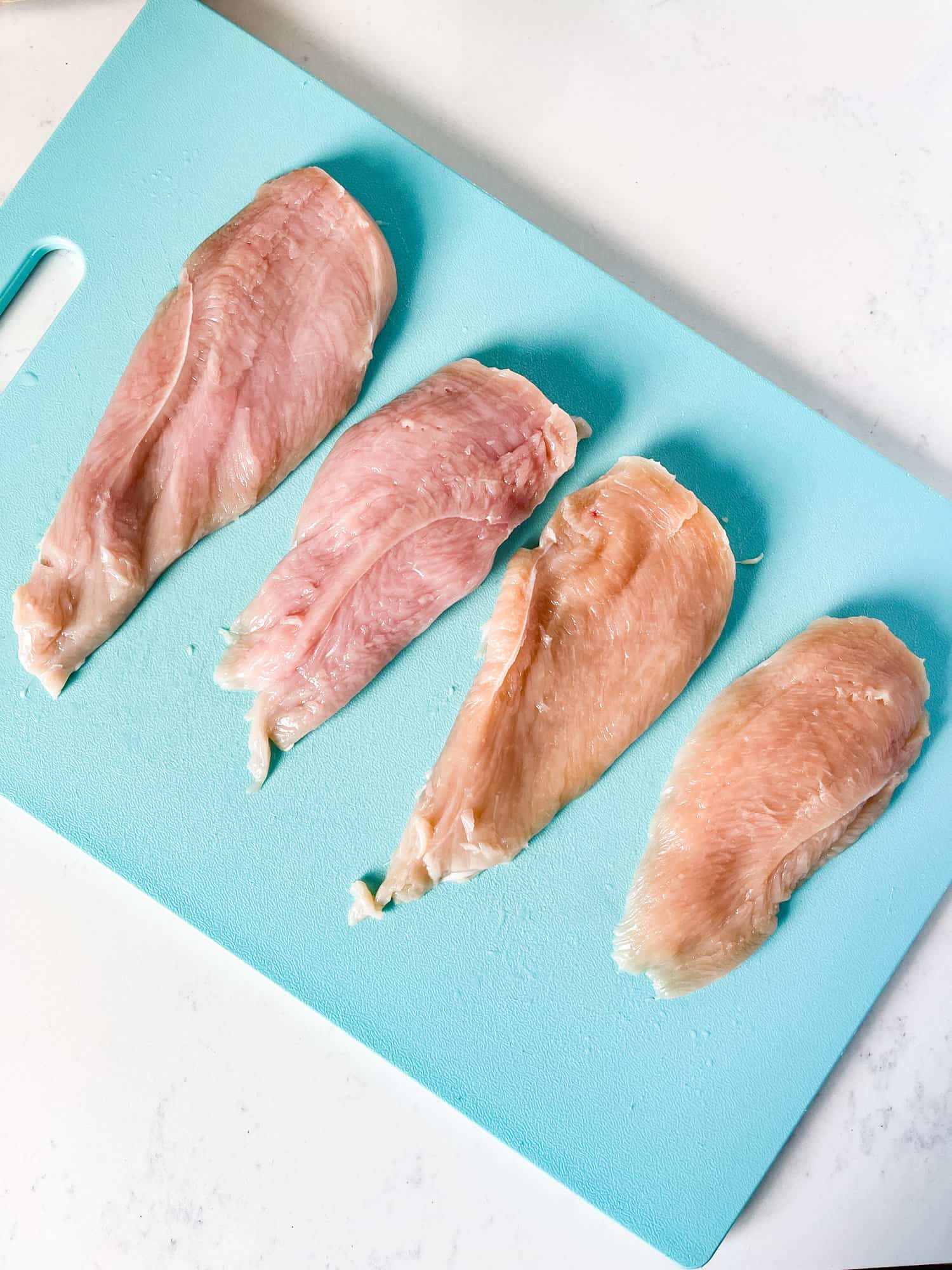 boneless chicken breast cut in half on a cutting board