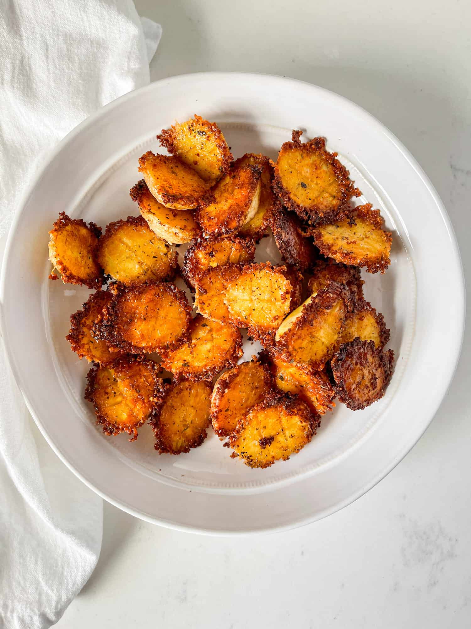 Parmesan crusted potatoes in a white serving bowl