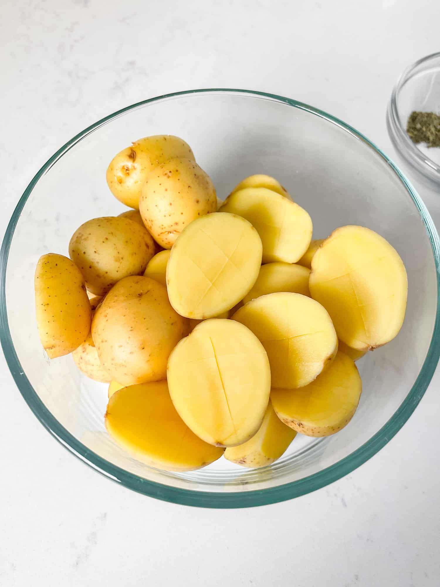 yukon gold potatoes cut in half and scored in a glass bowl