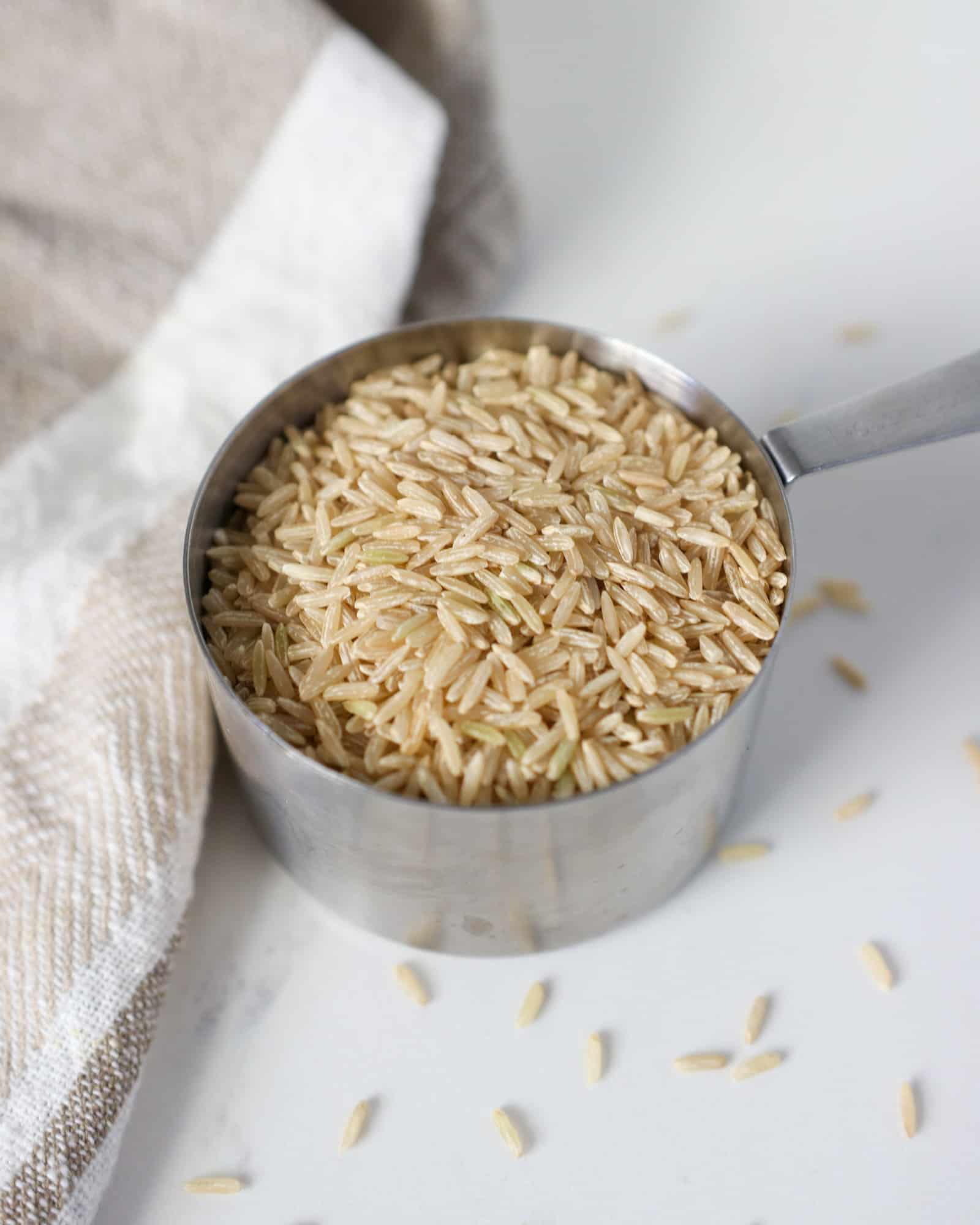 Brown Jasmine Rice in a measuring cup on a white counter