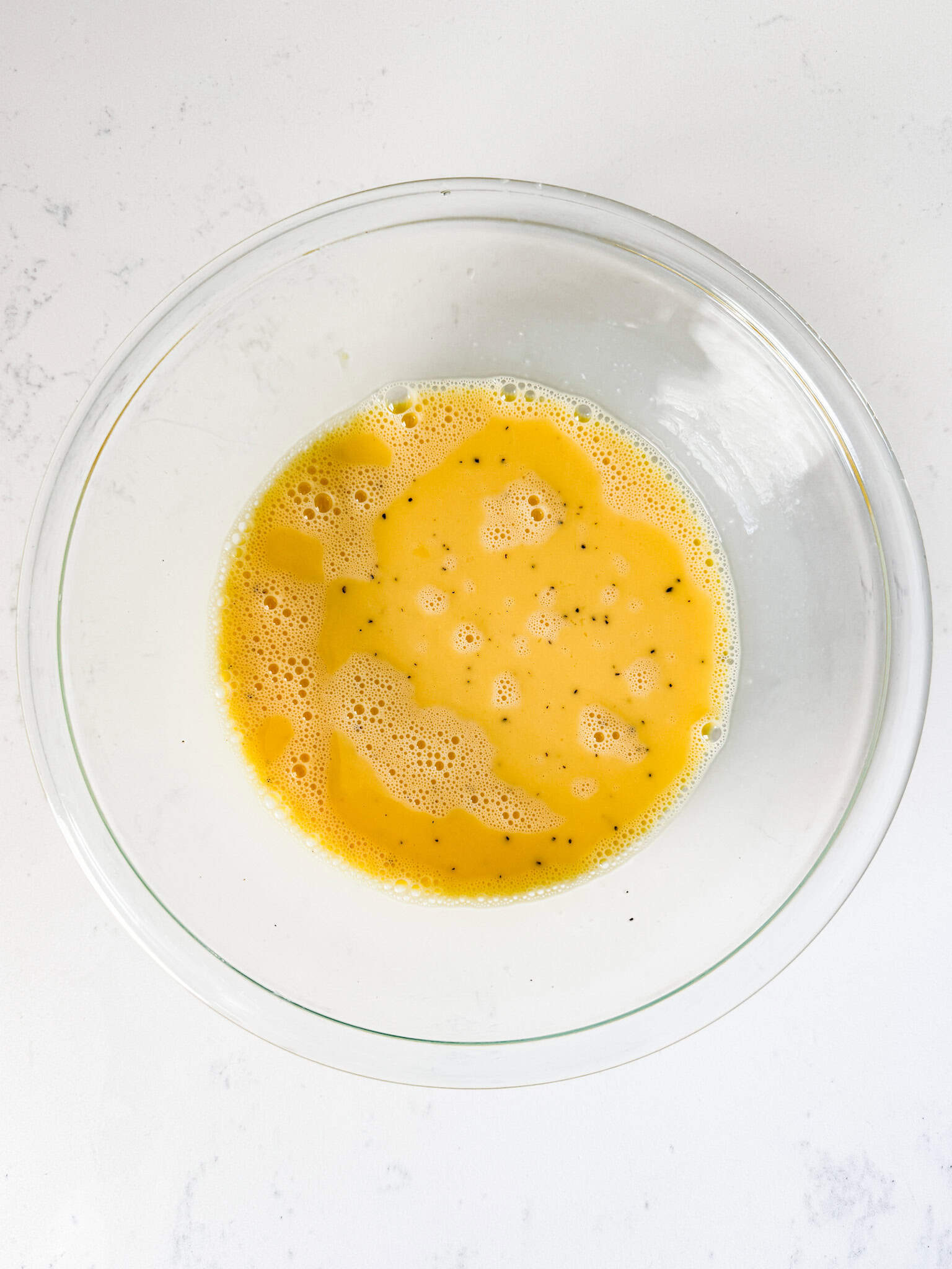 Beaten eggs in a glass bowl.