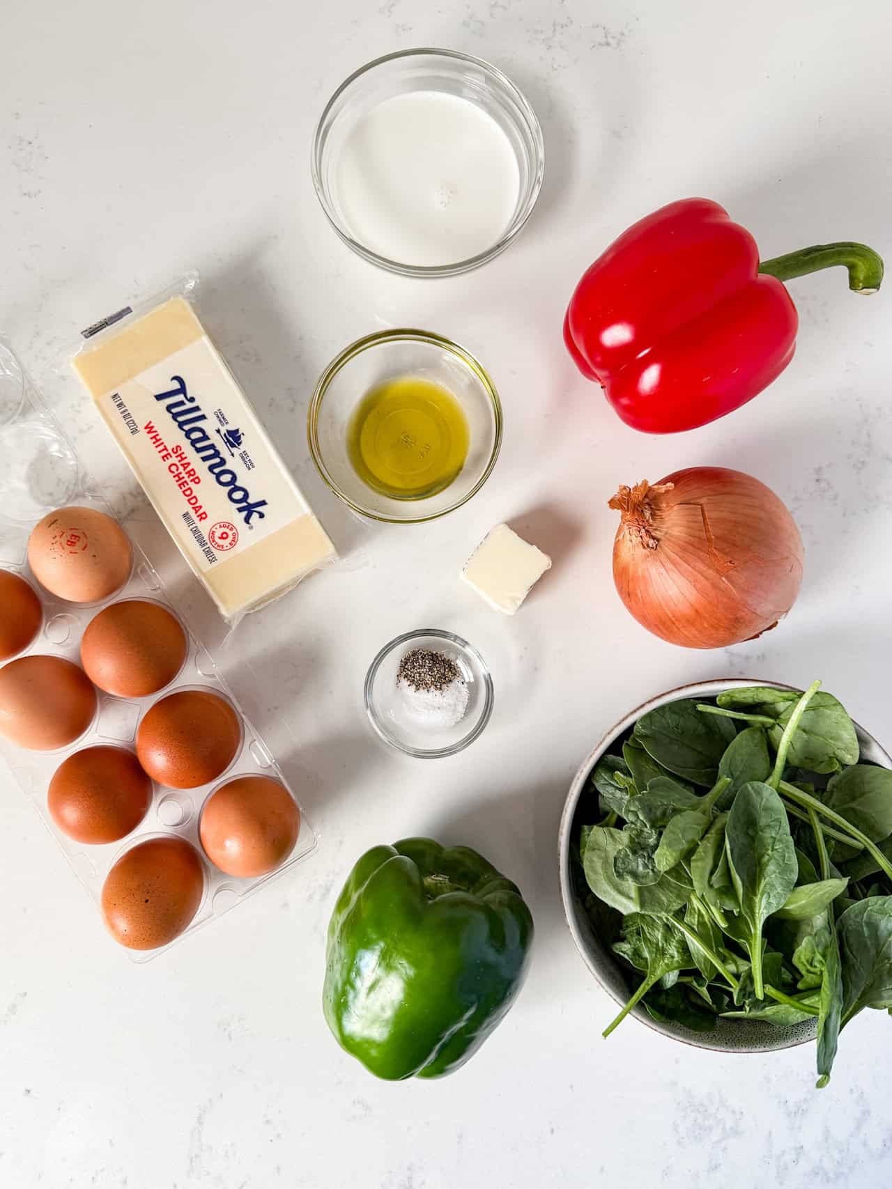 Overhead view of ingredients for a frittata on a white countertop.