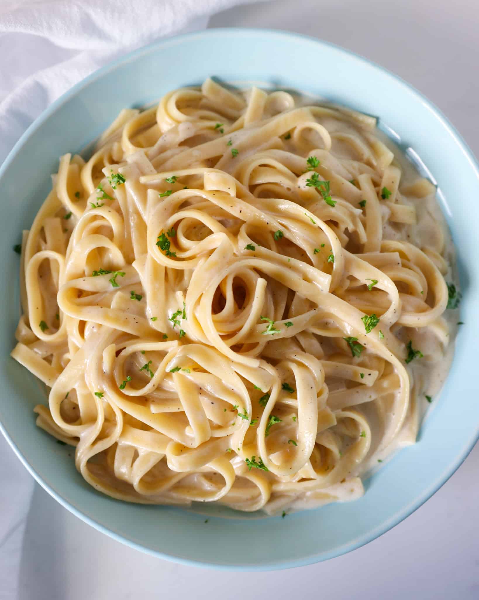 Instant pot fettuccine alfredo in a serving bowl garnished with parsley