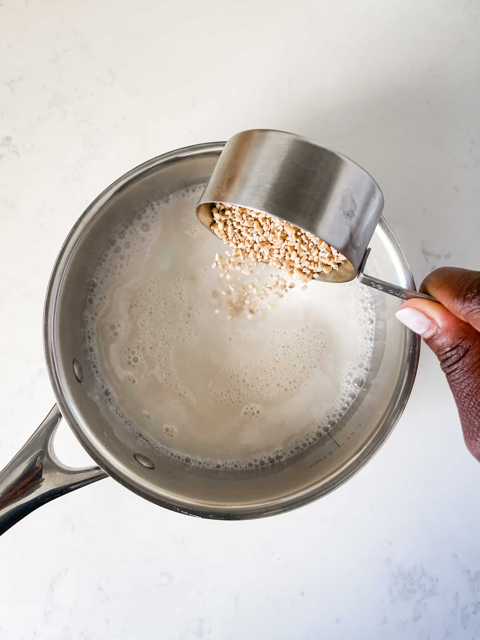 Pouring Steel Cut Oats into a saucepan with milk and water.
