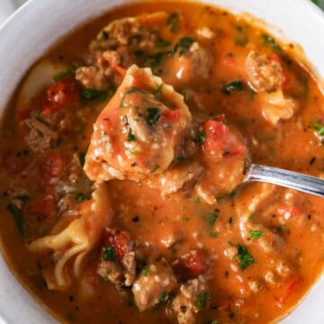 Overhead picture of creamy tortellini soup in a bowl with a soup lifting some out.