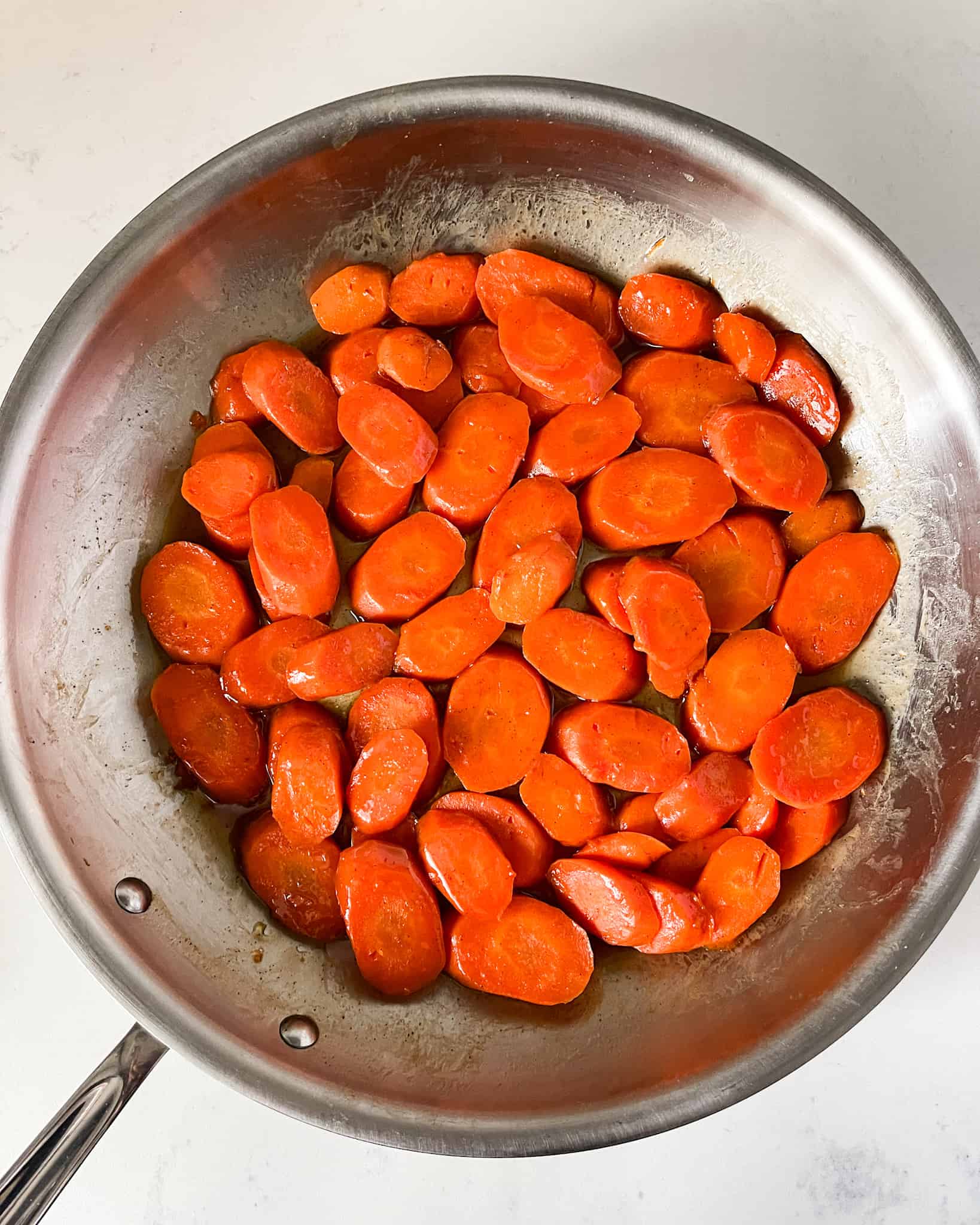 Cooked glazed carrots in a skillet.