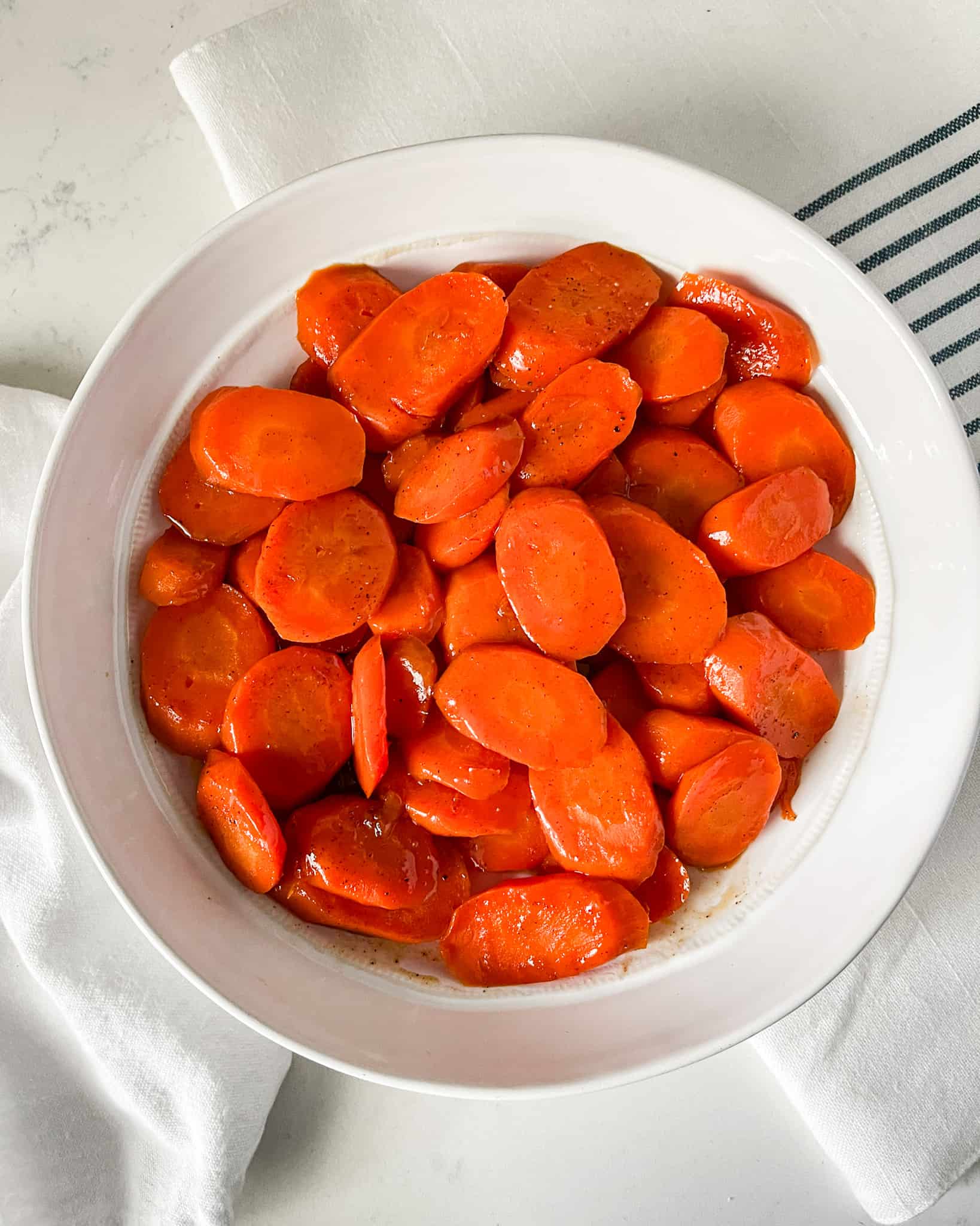 Glazed carrots in a white serving dish.