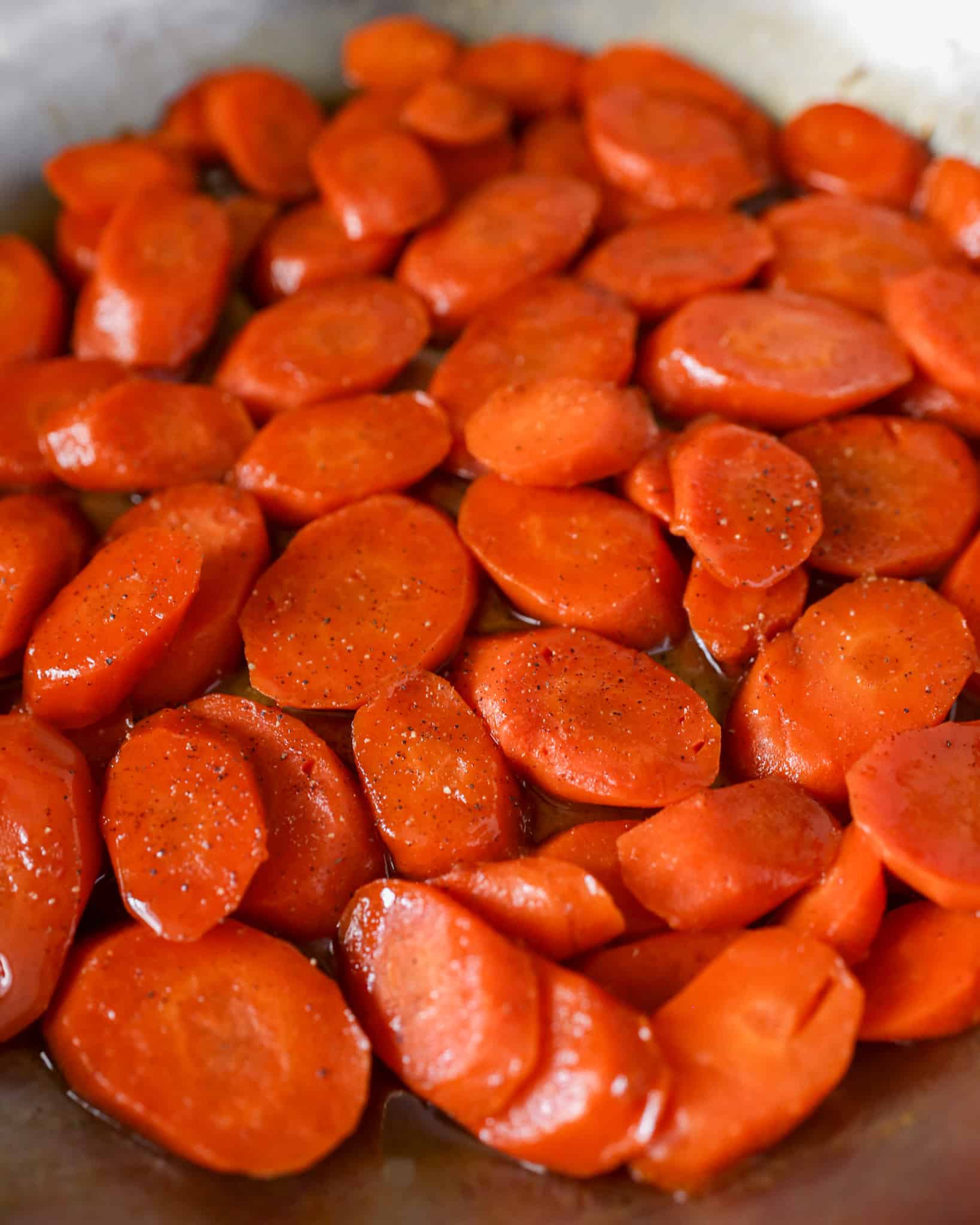 Close up view of glazed carrots in a skillet.