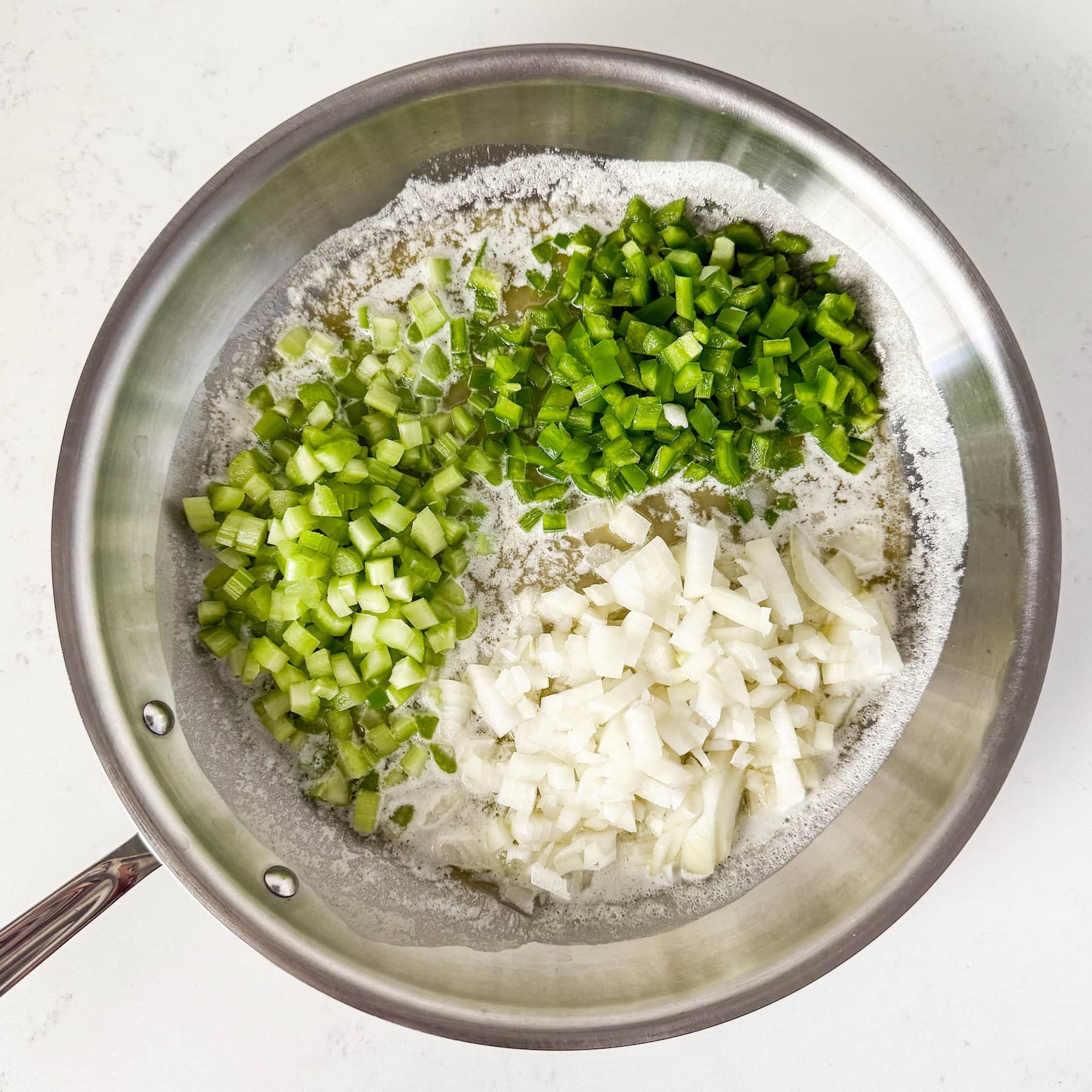 Diced celery, bell pepper, and onion in a skillet with butter.