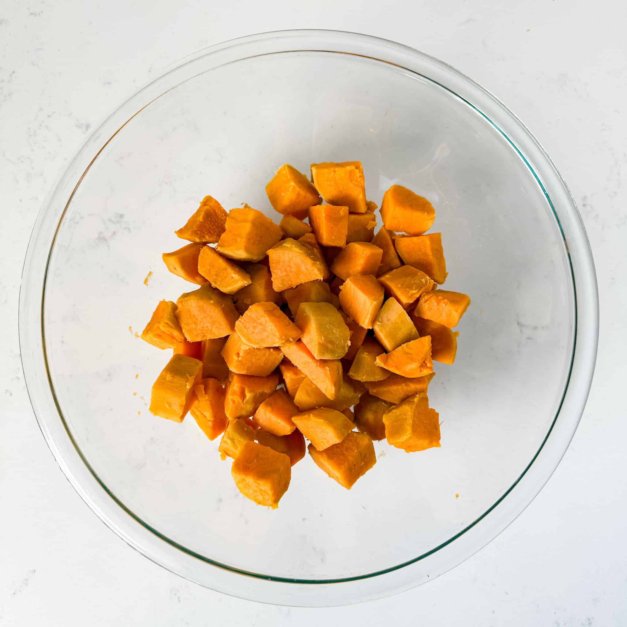 Cooked sweet potatoes drained and placed in a clear bowl.