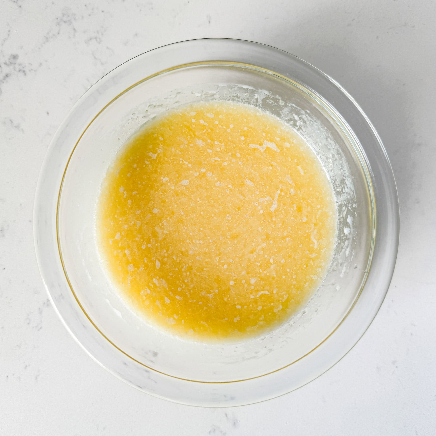 Cornbread wet ingredients mixed together in a glass bowl.