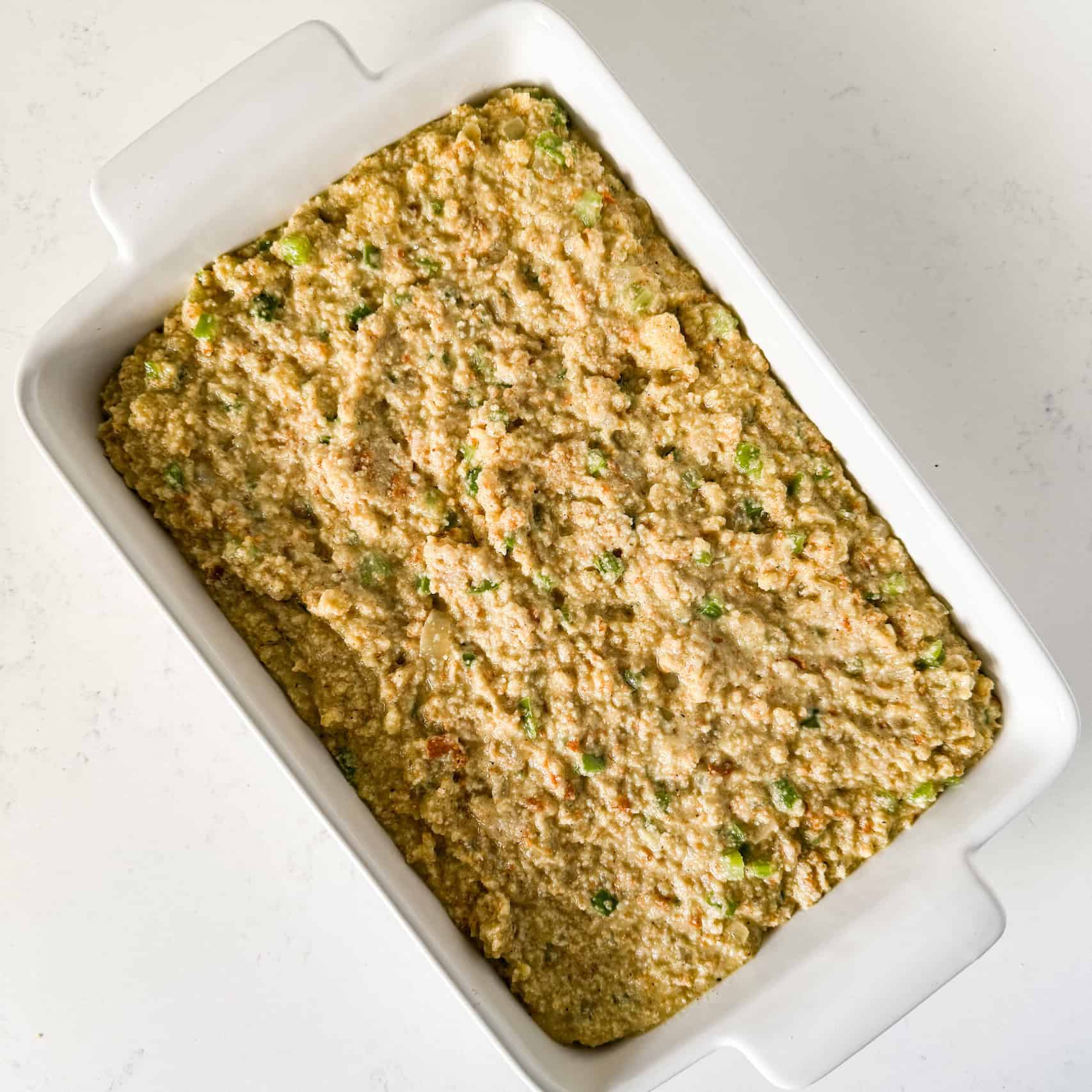 Cornbread dressing added to baking dish.