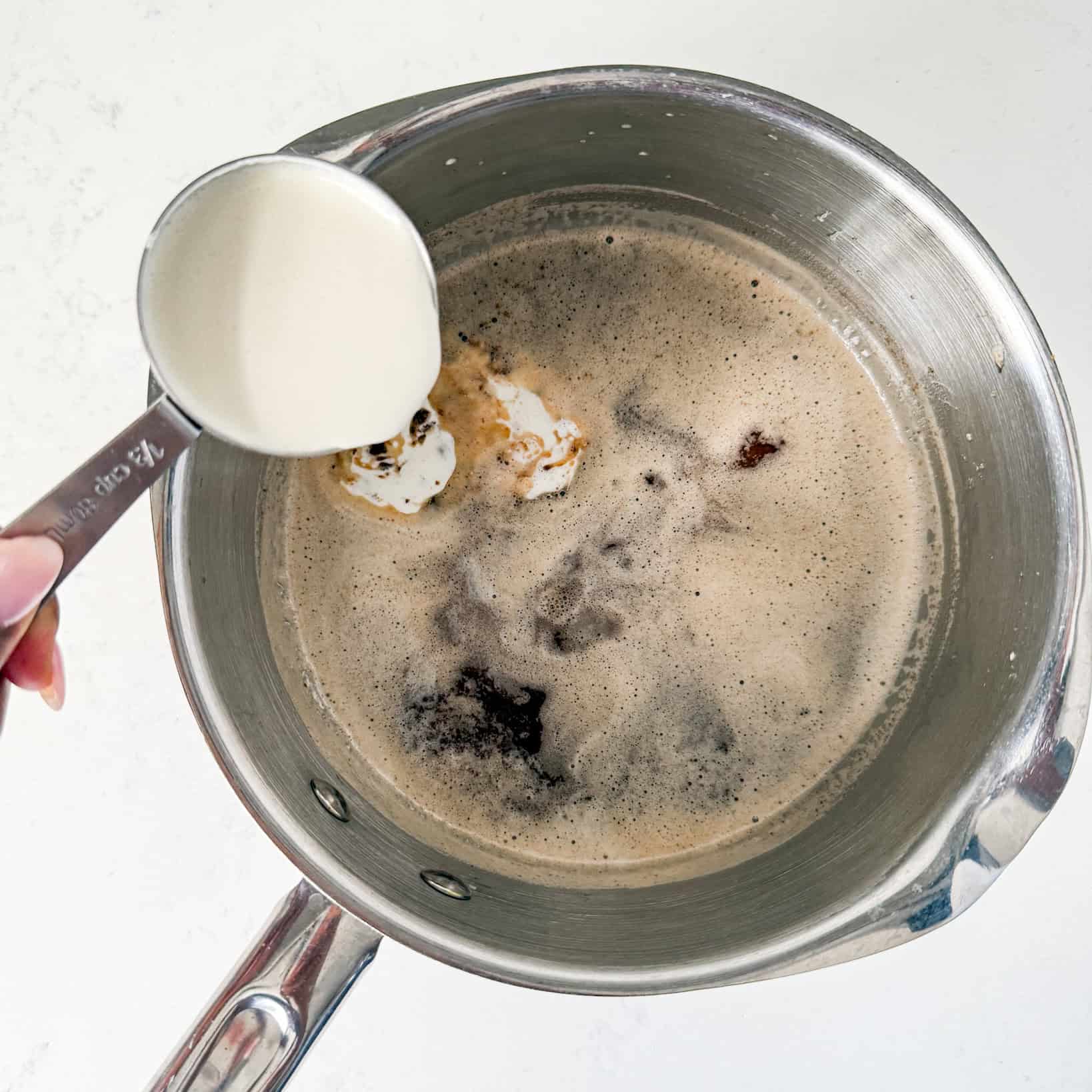 Cream being added to pot with brown butter and sugar.