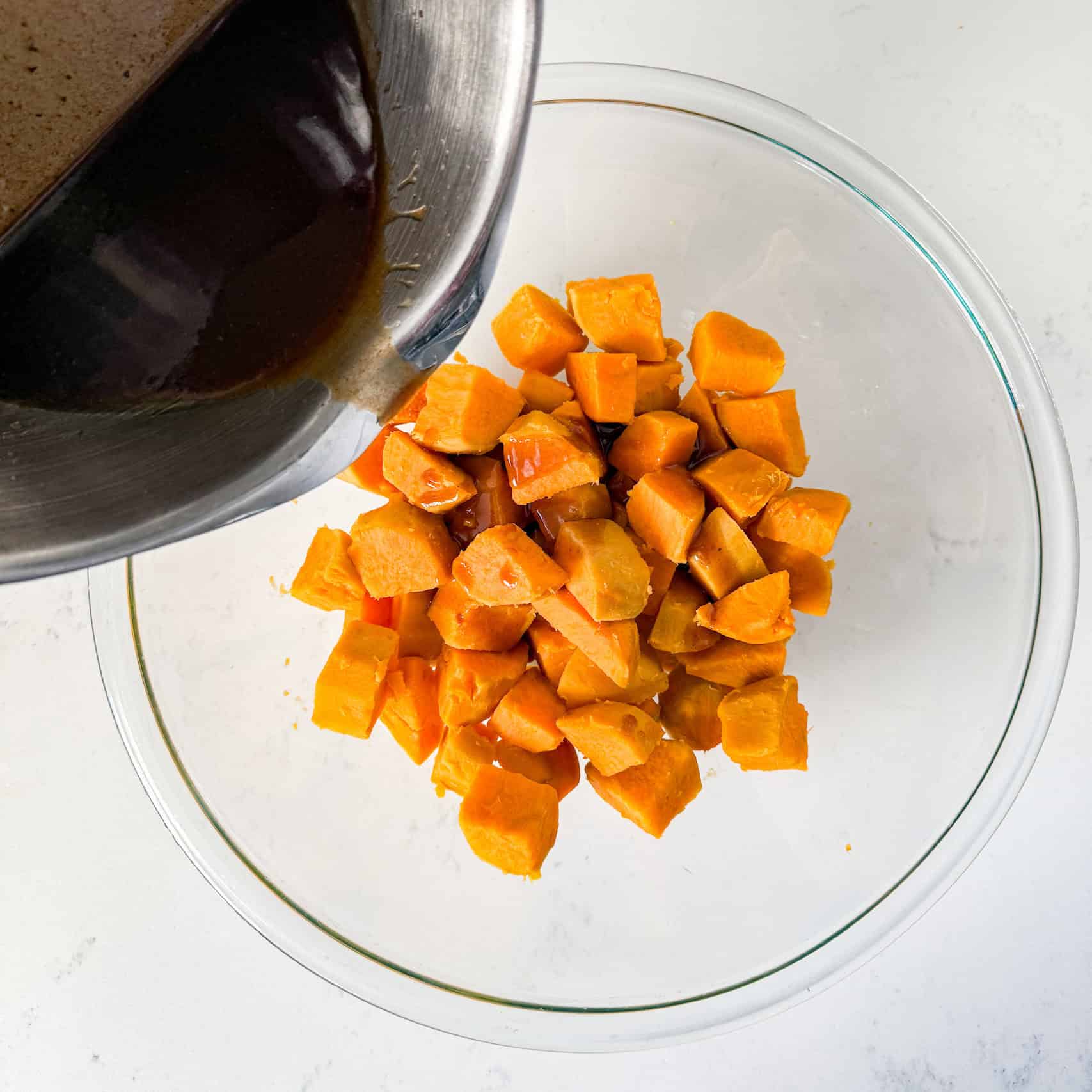 Brown butter mixture being poured over sweet potatoes