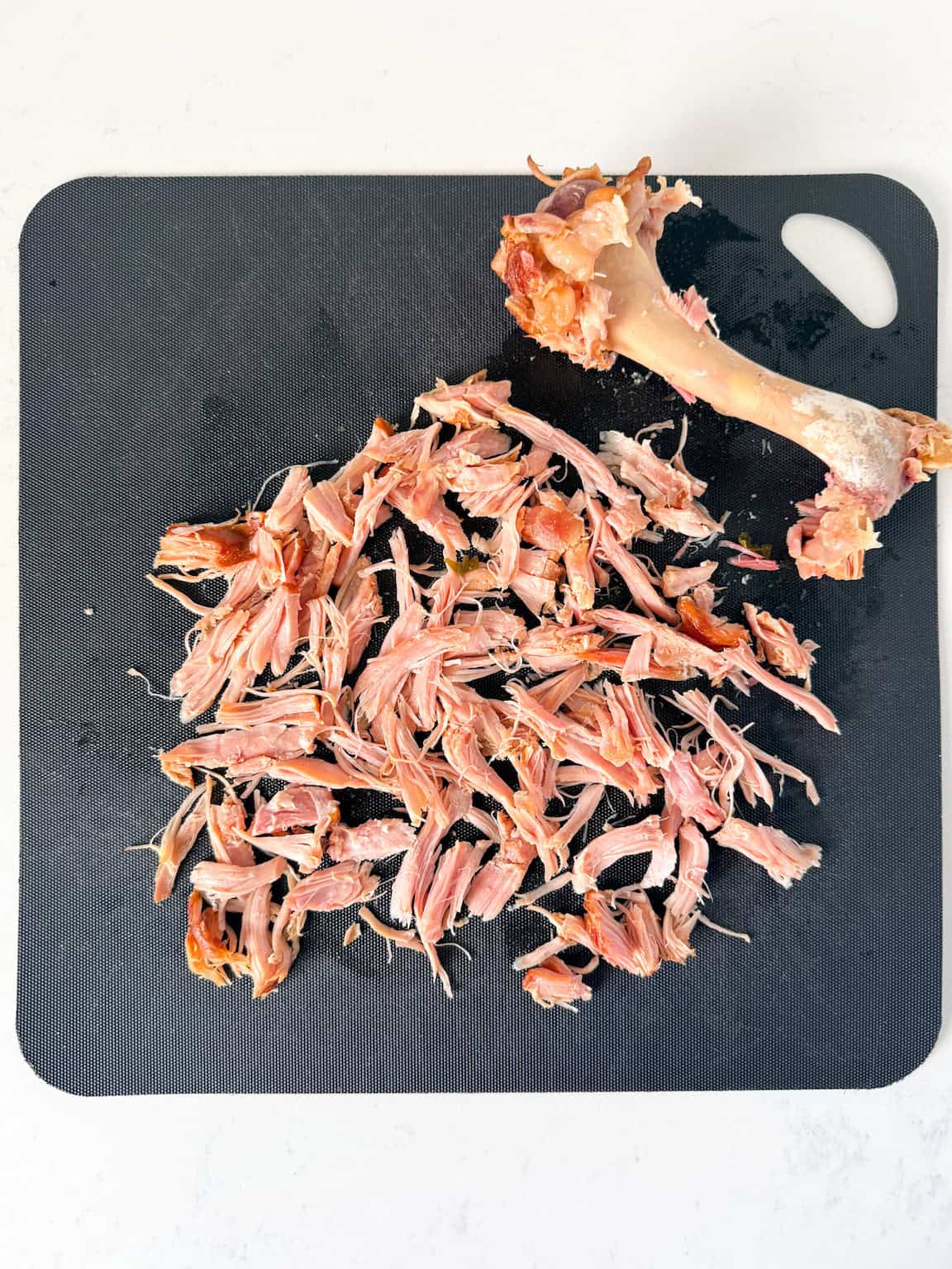 Smoked turkey meat pulled off the bone on a cutting board.