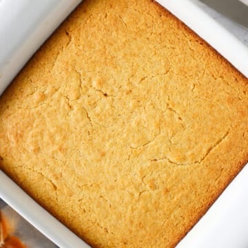 Overhead view of homemade cornbread in a white baking dish.