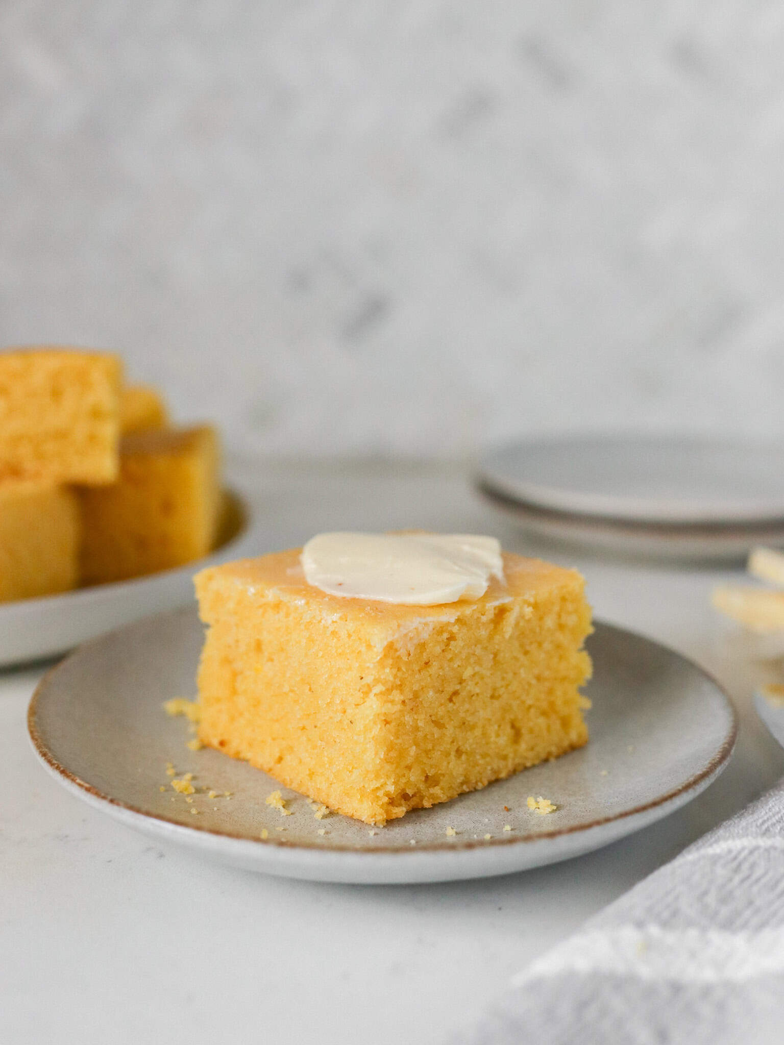 Front side view of a slice of homemade cornbread on a serving plate.