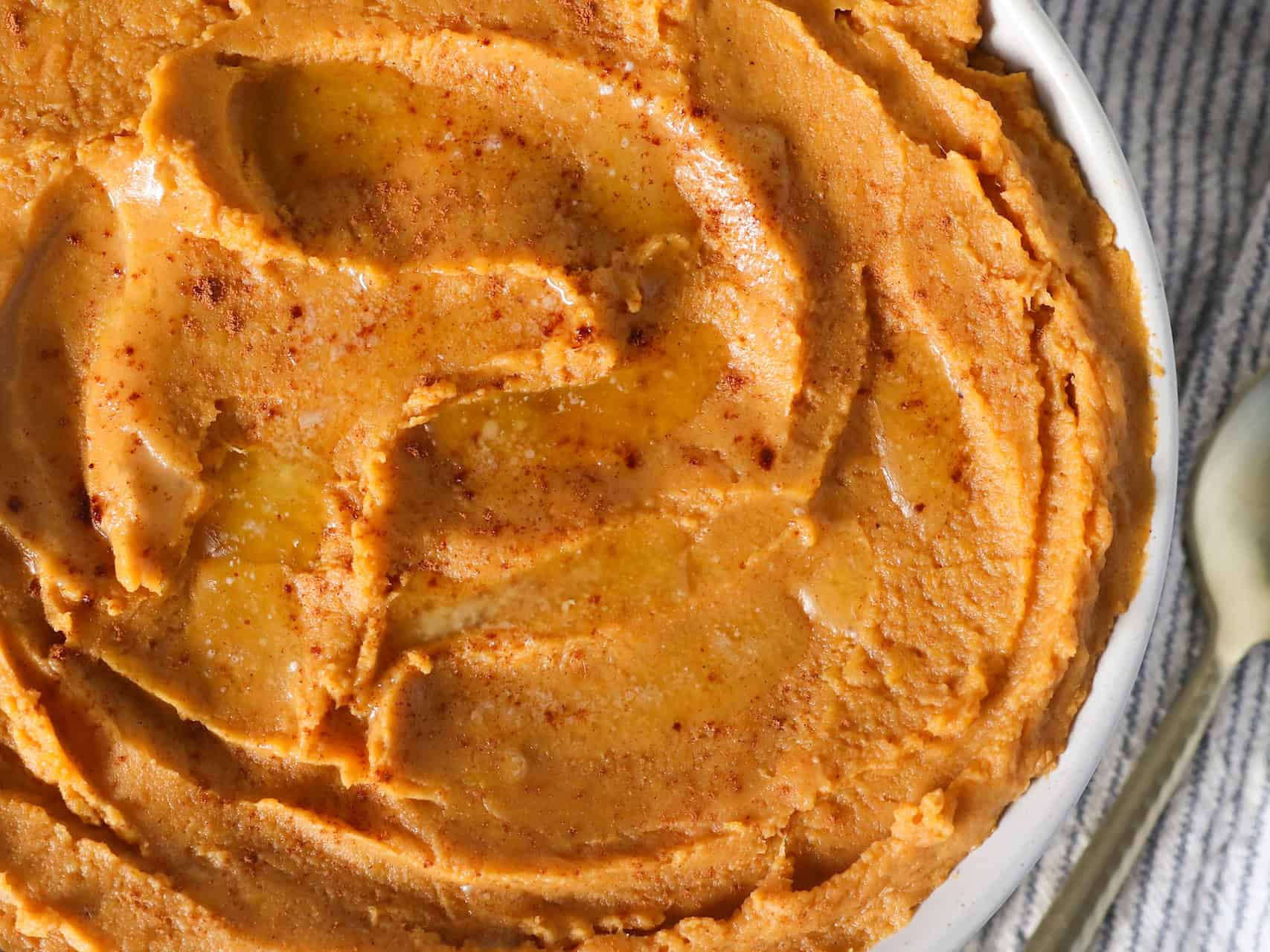 Overhead view of creamy mashed sweet potatoes in a white serving dish.