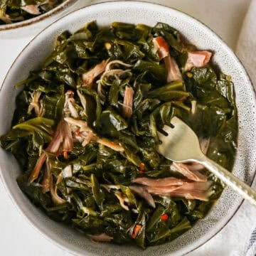 Overhead view of a bowl full of collard greens with smoked turkey and a fork lifting some out.