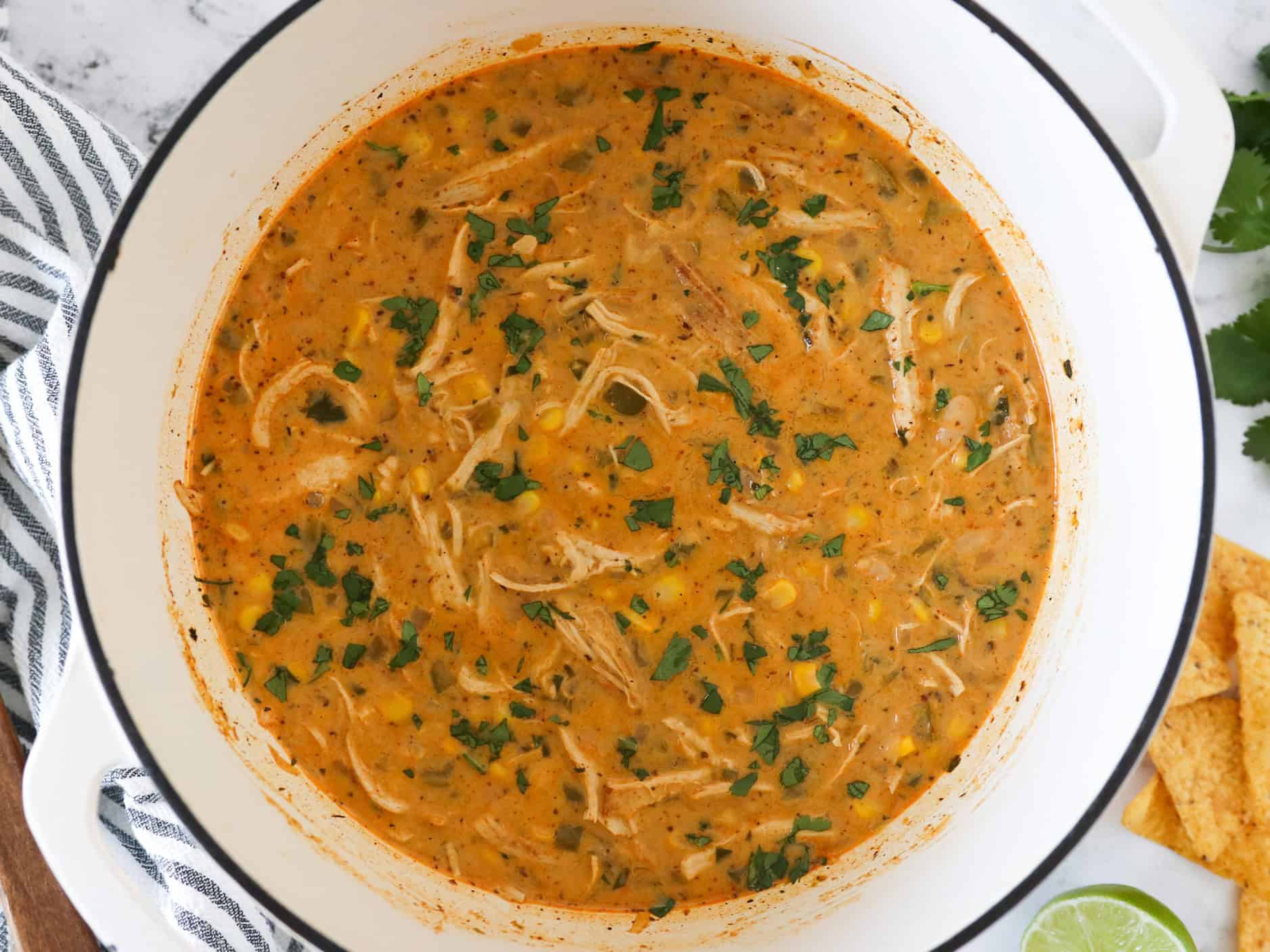 Overhead view of white chicken chili in a white dutch oven pot garnished with cilantro.