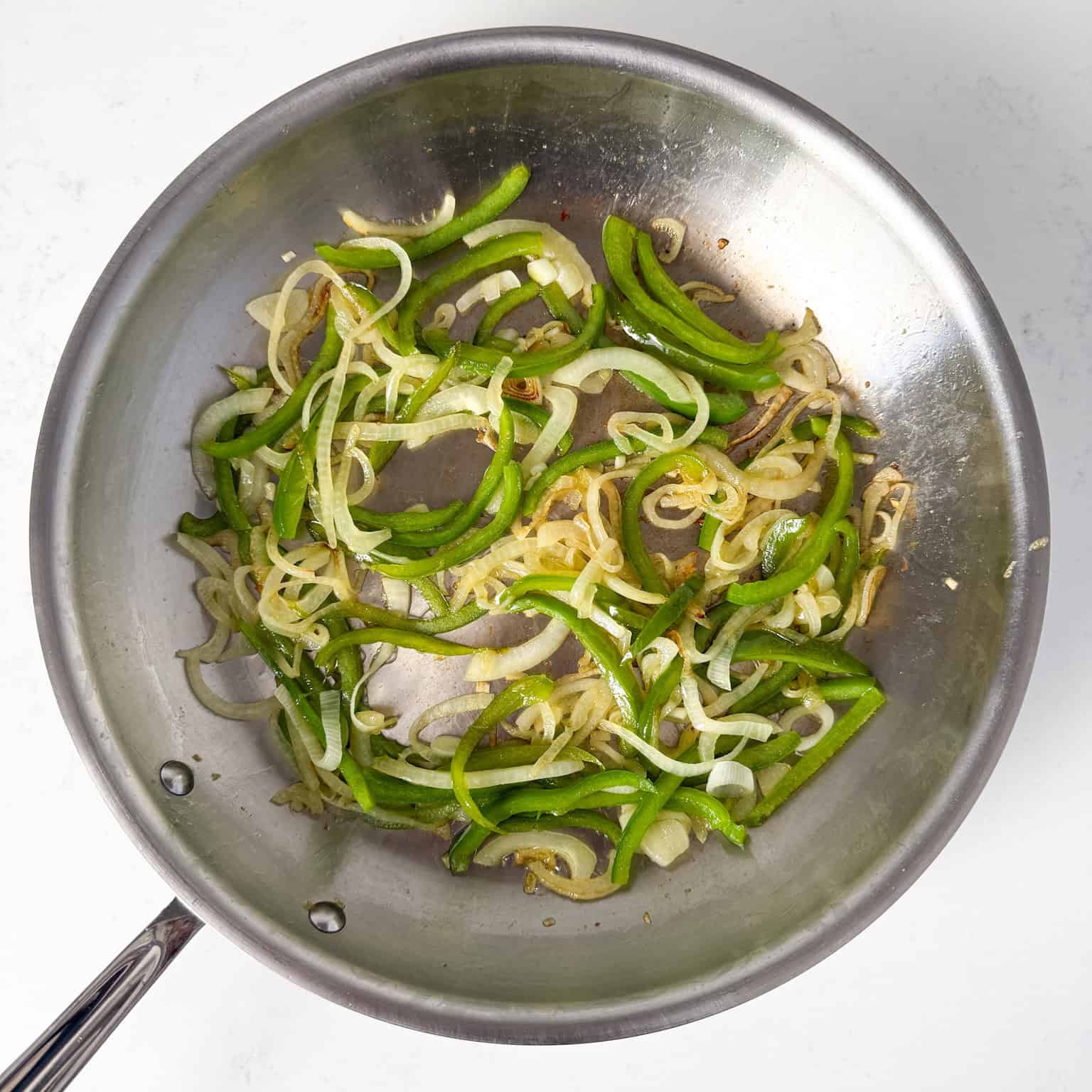 Sauteed peppers and onions in a skillet.