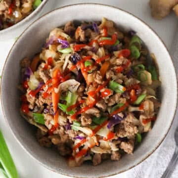 Overhead view of Egg roll in a bowl in a small serving bowl with a fork and green onions on the side.
