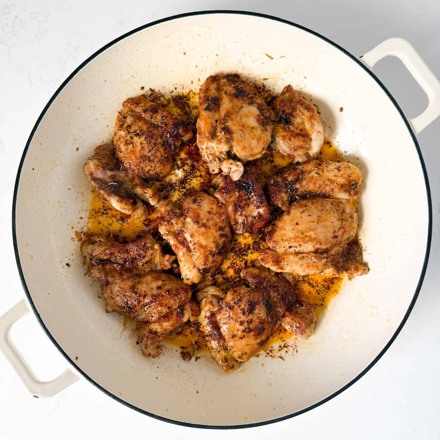 Seared chicken thighs in a large skillet.