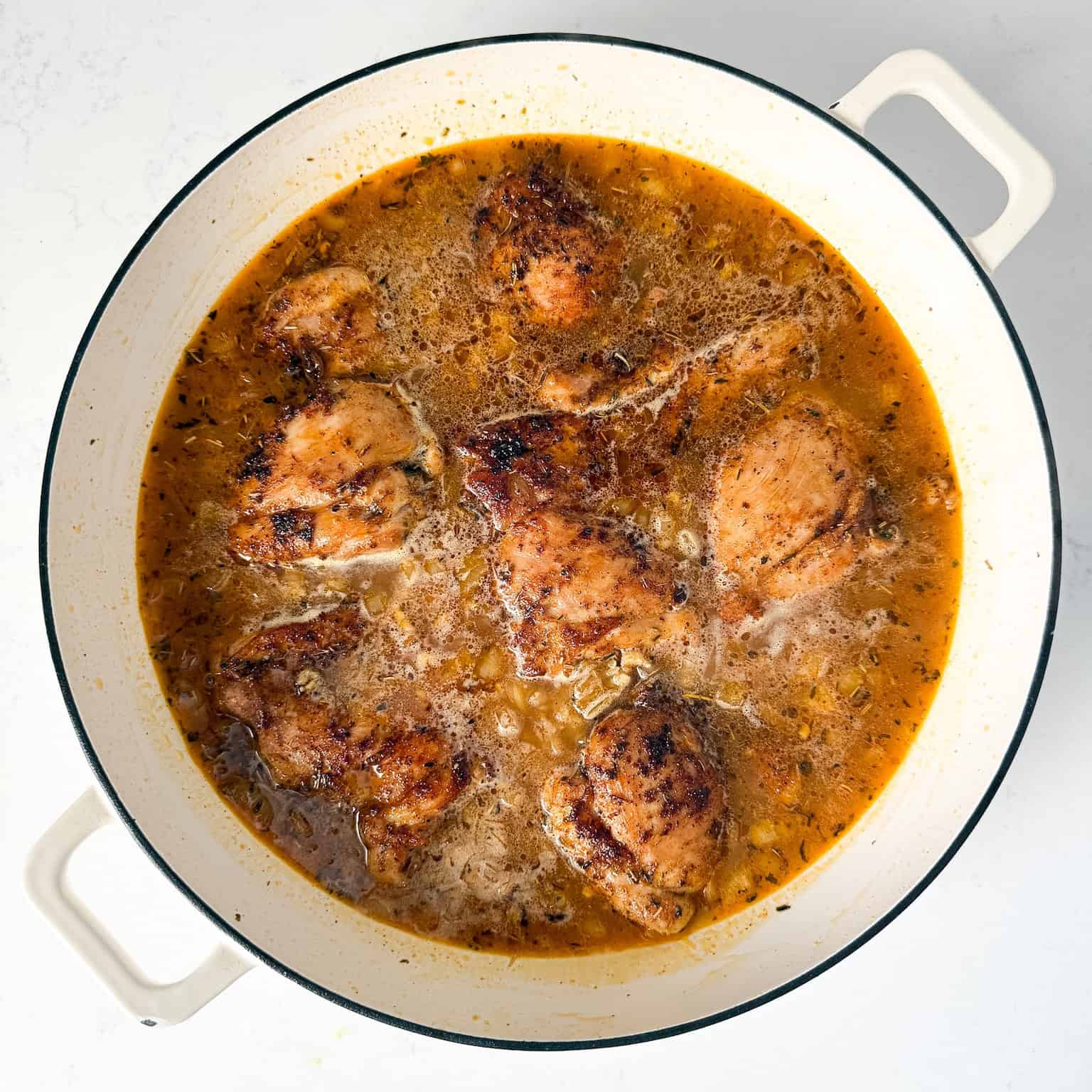 Chicken thighs added to skillet on top of orzo.