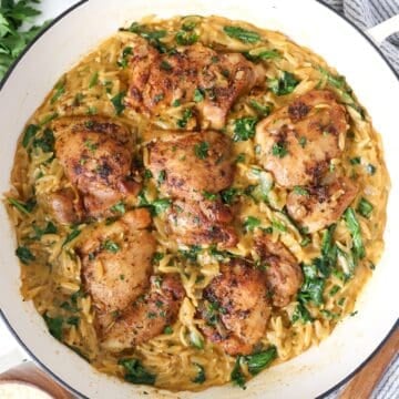 Overhead view of one pan chicken and orzo pasta in a white cast iron skillet.