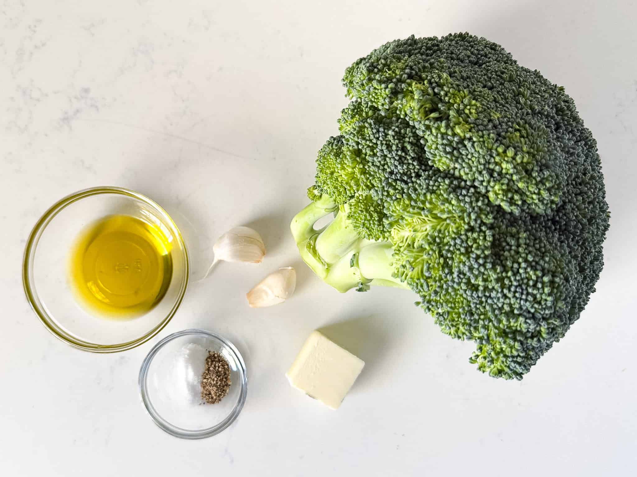 Ingredients for sautéed broccoli on a white countertop.
