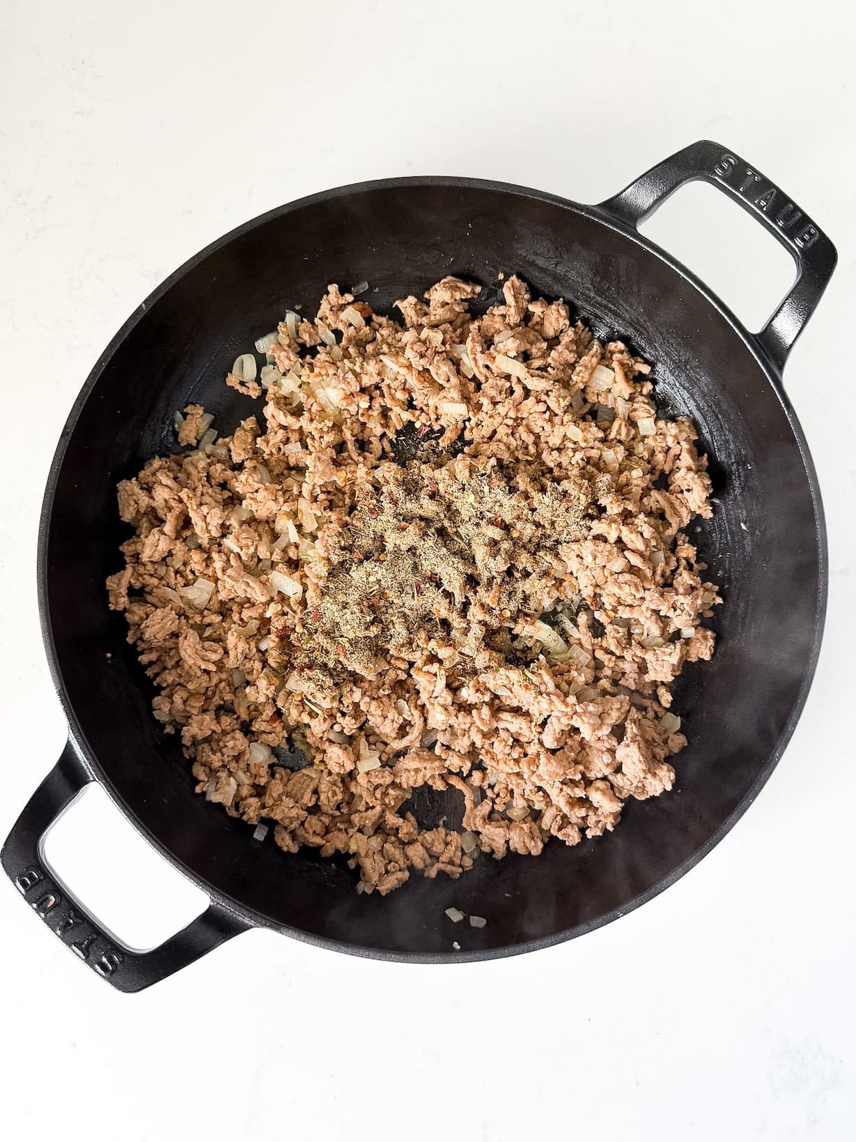 Spices and seasoning added to skillet.