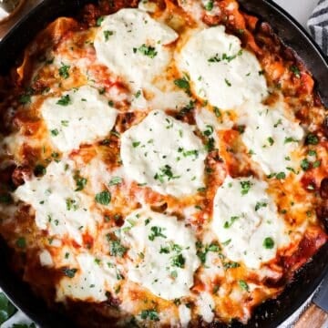 Overhead view of skillet lasagna in a black cast iron skillet with a wooden spoon on the side.