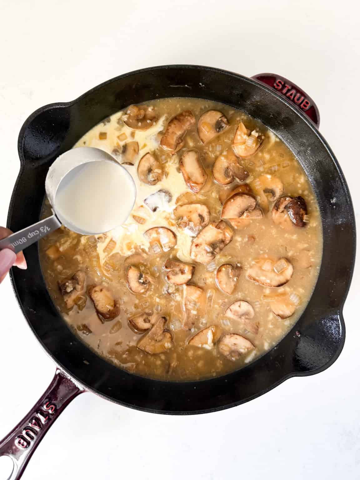 Chicken broth and heavy cream added to cast iron skillet.