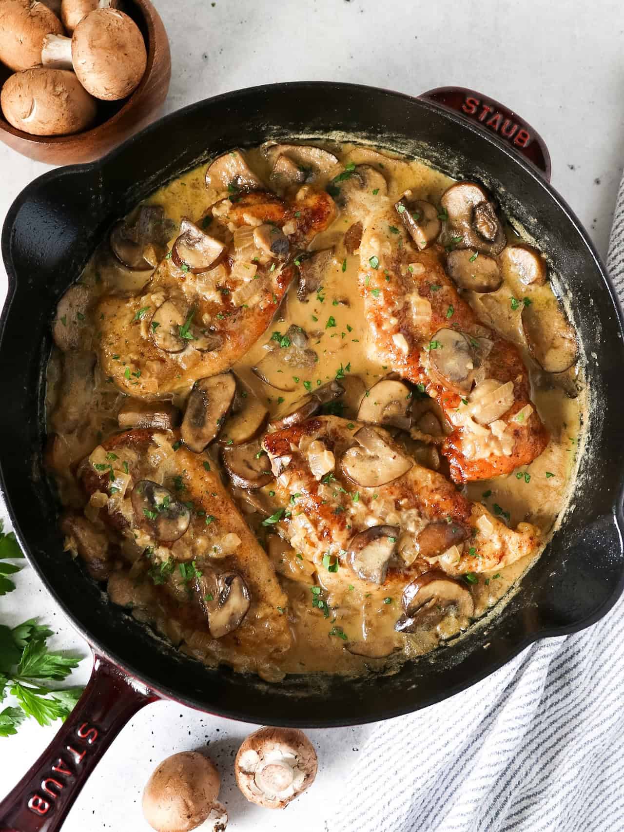 Overhead view of creamy mushroom chicken in a cast iron skillet with a napkin on the side.