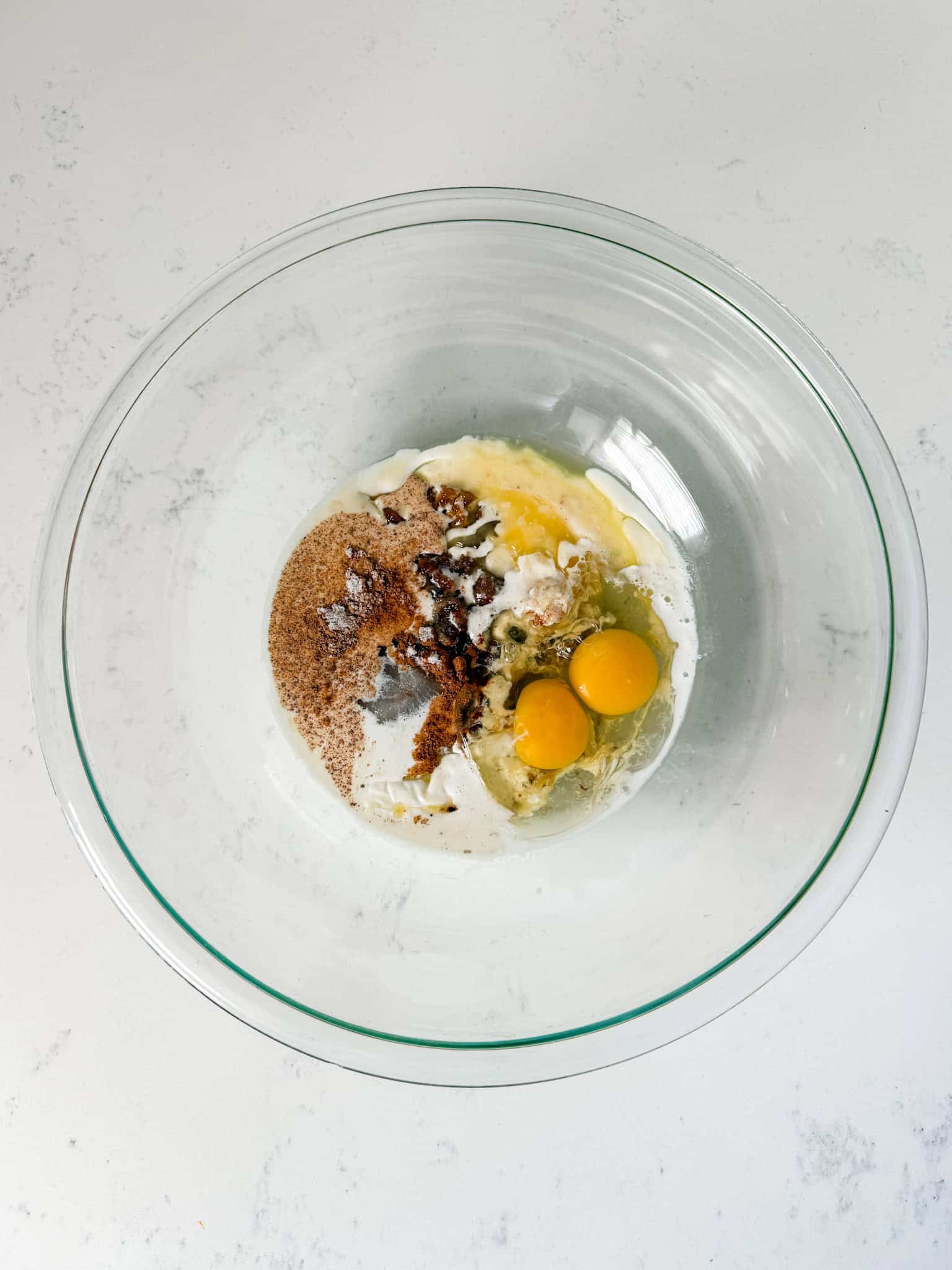Wet ingredients for sweet potato casserole in a glass bowl.