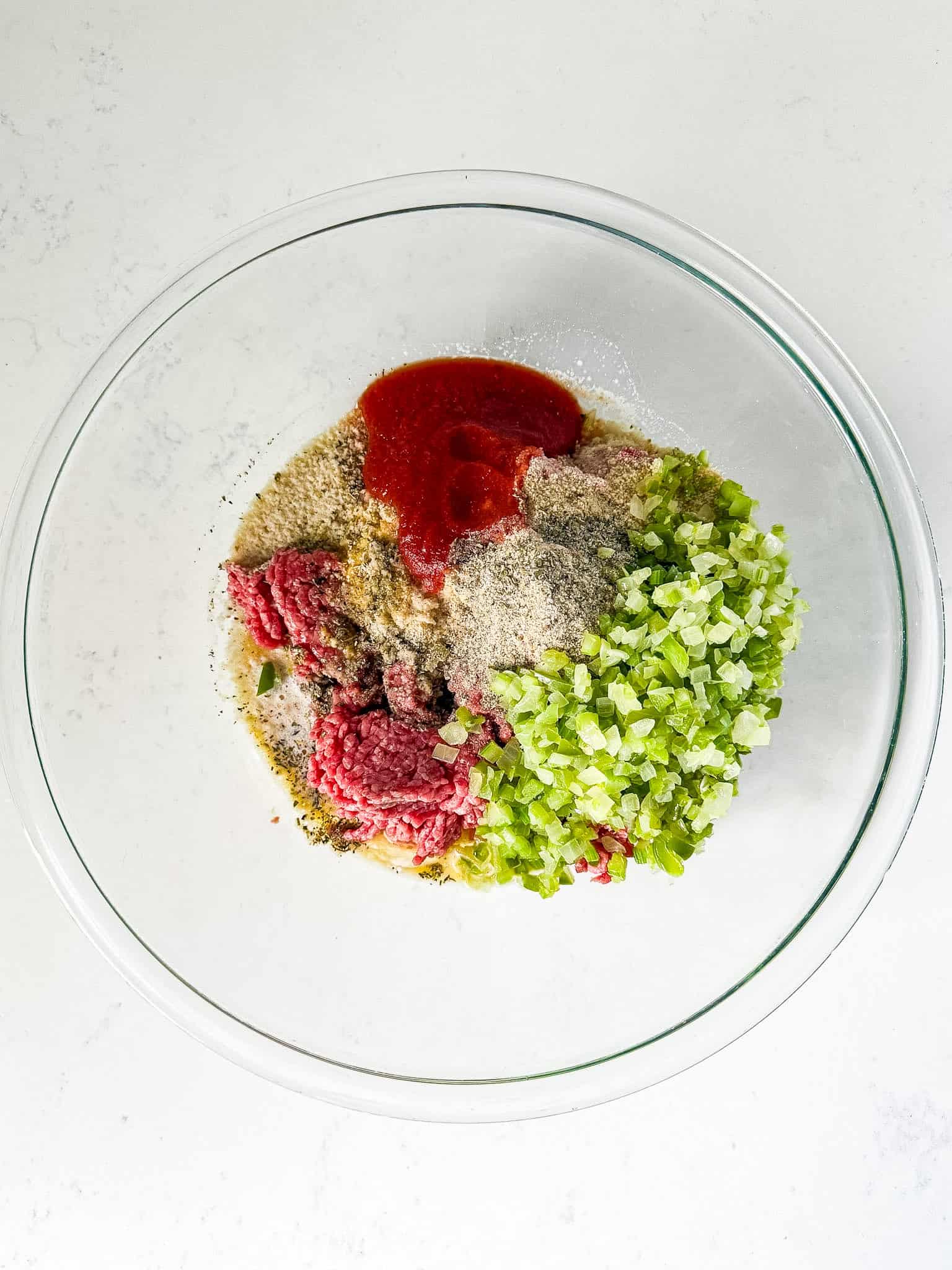 Ingredients for meatloaf in a large glass bowl
