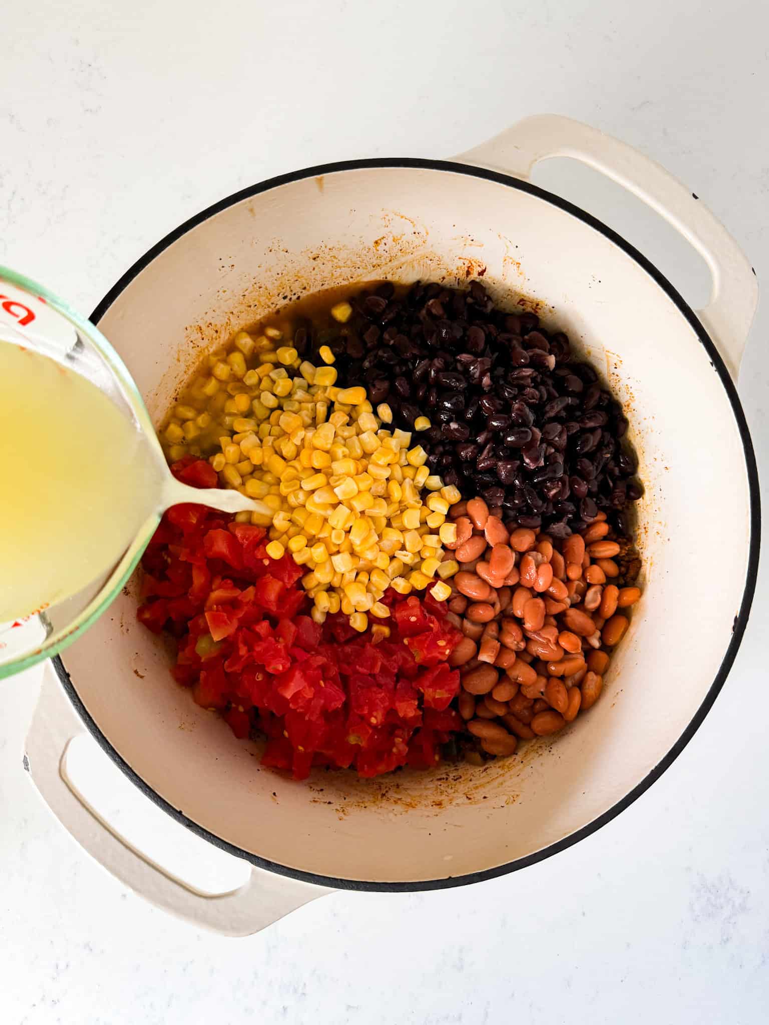 Diced tomatoes, beans, corn, and chicken broth added to the pot.