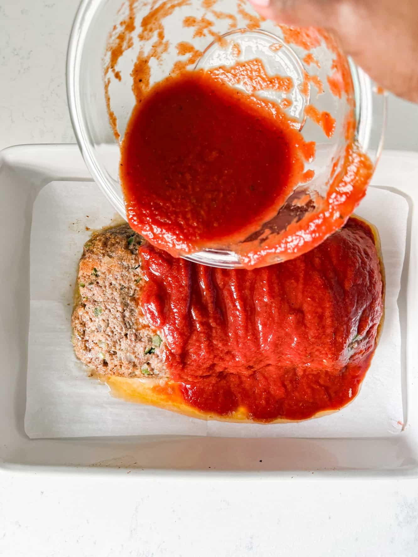 Meatloaf sauce being poured over meatloaf.