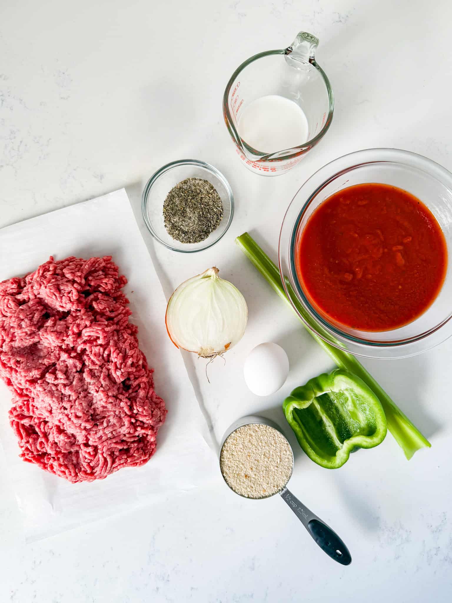 Ingredients for meatloaf recipe spread out on a white countertop.