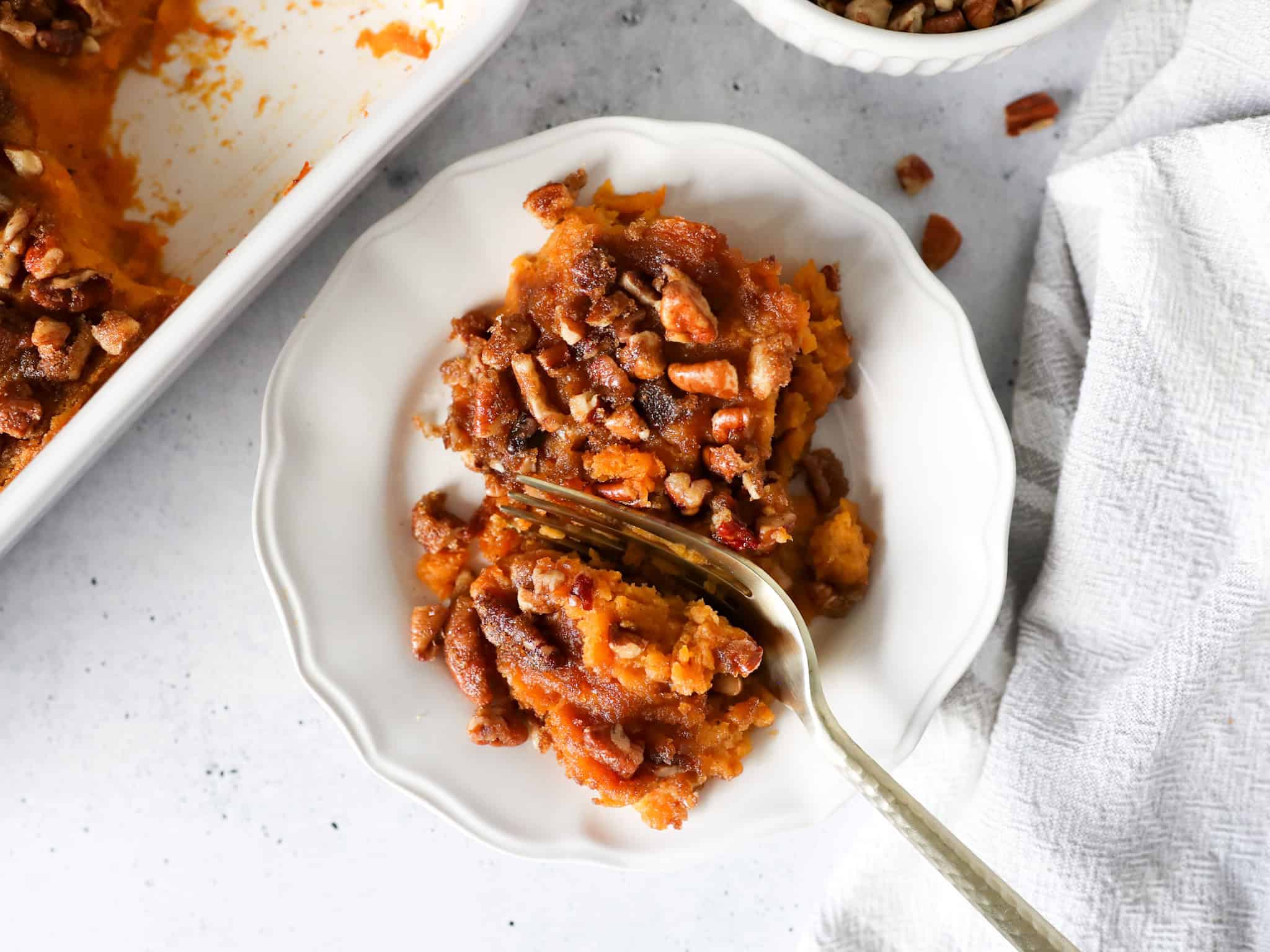 Overhead view of a serving of sweet potato casserole on a white plate.