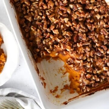 Overhead view of sweet potato casserole with some scooped out on a plate.